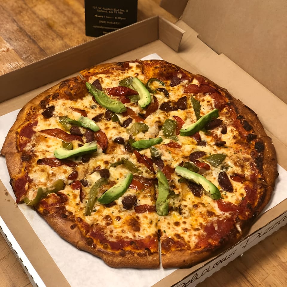 A Upland Pizza Company pizza with avocado, pepperoni, and green peppers in a delivery box.
